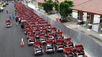 Barisan becak listrik berwarna-warni yang baru dibagikan terparkir rapi, dengan latar belakang Pendopo Delta Wibawa Sidoarjo.