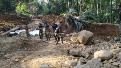 Prajurit TNI mengenakan seragam loreng sedang menyemprot lumpur di ruang kelas sebuah sekolah yang terdampak bencana di Tapanuli Tengah.”