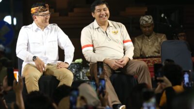 Bupati Sumedang Dony Ahmad Munir mengenakan kemeja putih dan ikat kepala khas Sunda sedang mengangkat tangan disambut ribuan massa di Alun-alun Sumedang.