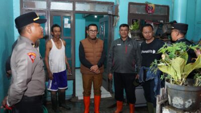 Wali Kota Batu Nurochman berjalan di antara lumpur dan genangan banjir saat meninjau Dusun Banyuning, Desa Punten
