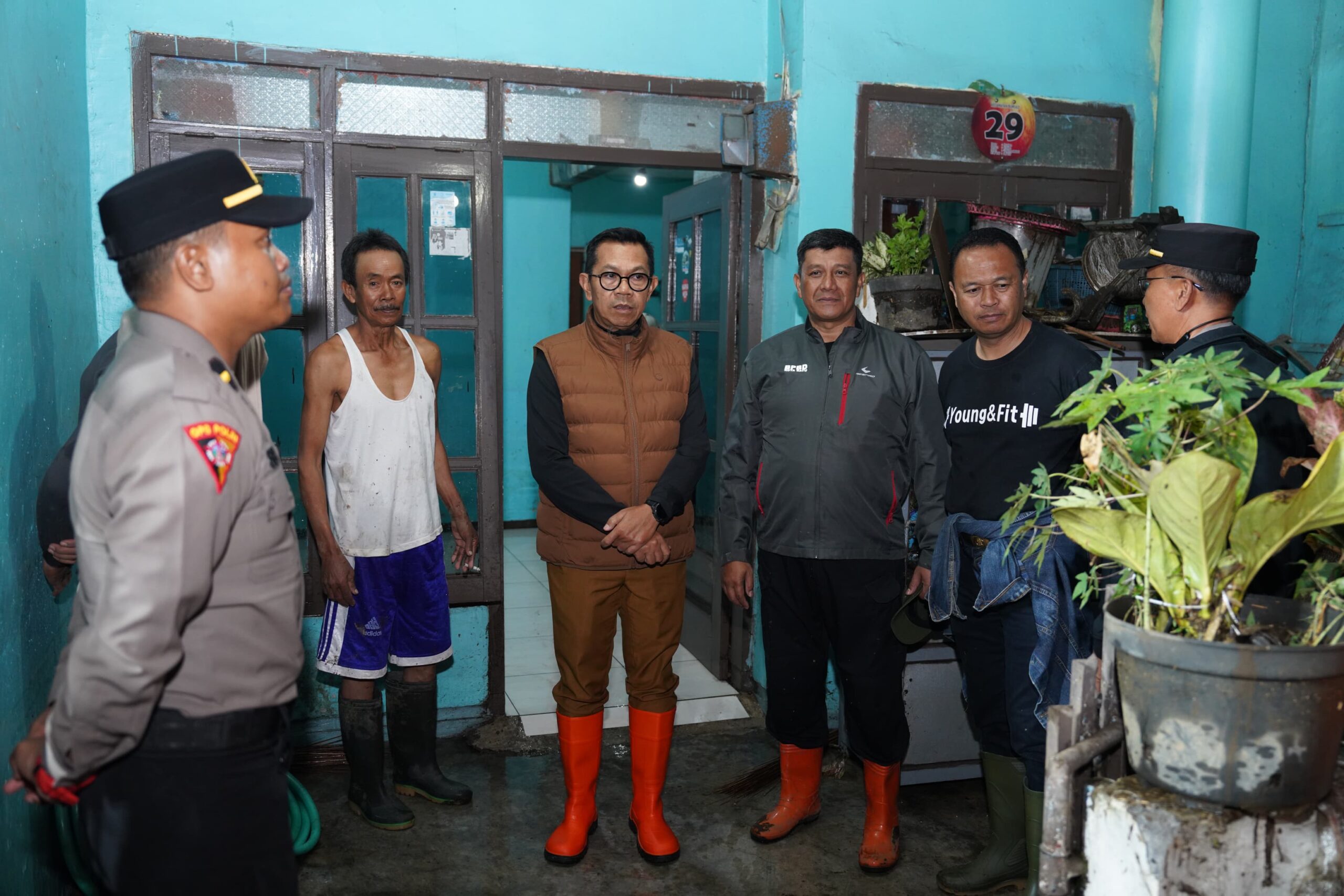 Wali Kota Batu Nurochman berjalan di antara lumpur dan genangan banjir saat meninjau Dusun Banyuning, Desa Punten