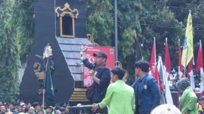 Ketua Umum Bapemnus Jansen Henry Kurniawan berpidato di podium dengan latar bendera organisasi.